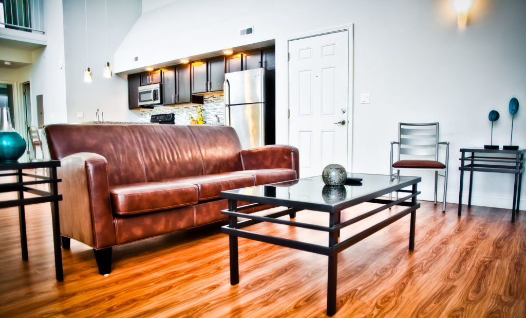 Luxury UIUC loft apartment with brown leather couch and glass coffee table.