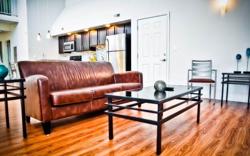 View of UIUC apartment living room with brown sofa and glass coffee table.