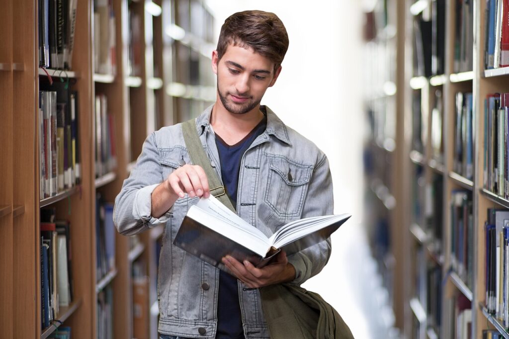 Student in library opening and reading book.