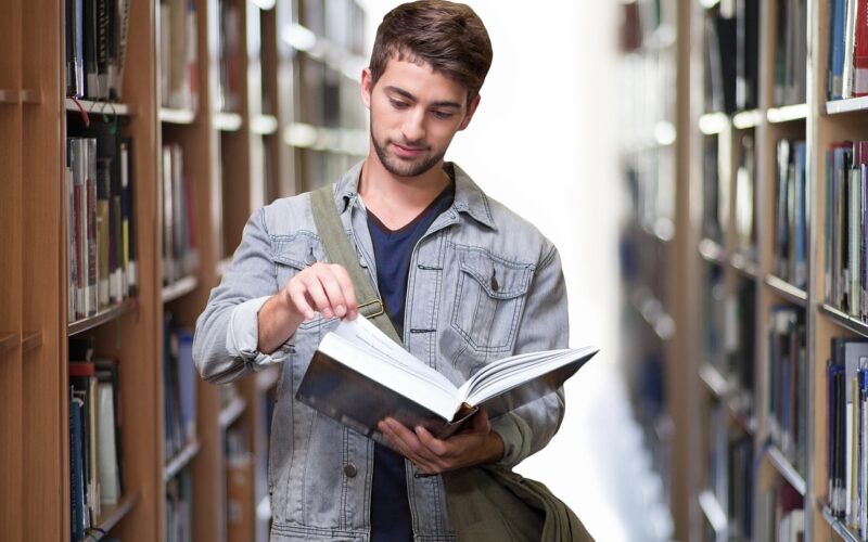 Student in library opening and reading book.