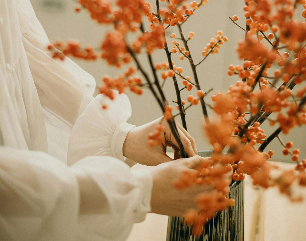 Close up of woman putting fall flowers in a vase